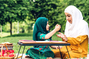 Wall Mural - Portrait of happy religious enjoy happy love asian islam family muslim mother and little muslim girls child with hijab dress smiling and having fun moments good time in summer park