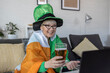 Mature woman with irish flag on shoulders holding glass of beer and celebrate saint patrick day