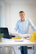 © epiximages - Architect with blue shirt is standing at height adjustable work table and is working