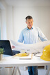 © epiximages - Architect with blue shirt is standing at height adjustable work table and is working