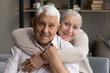 © fizkes - Happy senior married couple video call screen head shot. Cheerful grey haired wife hugging elderly husband from behind with love, enjoying close relationships, looking at camera, smiling