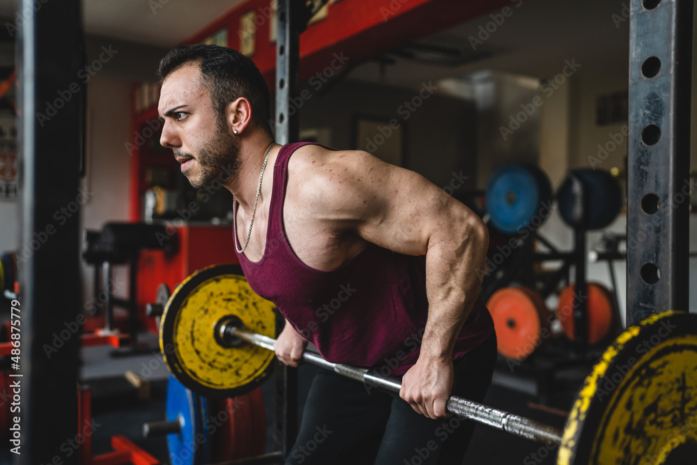 Male Bodybuilder Side View Rows one man side view of adult male bodybuilder standing at the gym lifting ...