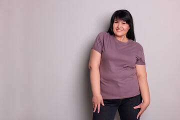 Wall Mural - Beautiful overweight mature woman with charming smile on light grey background. Space for text