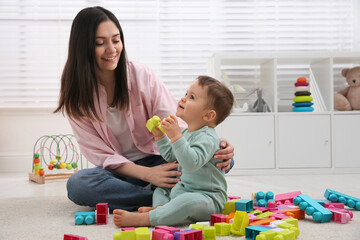 Poster - Cute baby boy playing with mother and building blocks on floor at home