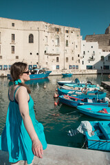 Wall Mural - Woman with a blue dress in the picturesque marina of Monopoli, a a little village in south Italy in summer