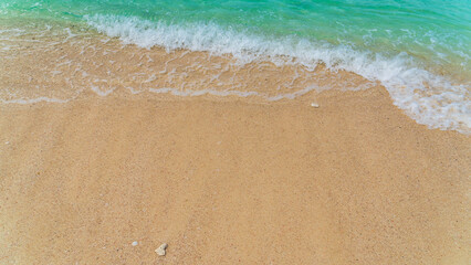 Sand beach seaside with white foamy and blue waves from the sea