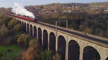 Aerial Shot Of Red Steam Train Crossing Viaduct In UK