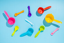 Multi-colored Measuring Spoons On A Blue Background. Flat Lay, Top View.