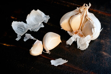 Wall Mural - Peeling and Sectioning a Head of Garlic on a Wood Table: Head of garlic with peel and cloves on a dark background