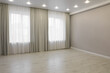 Empty room with beige wall, large window and wooden floor