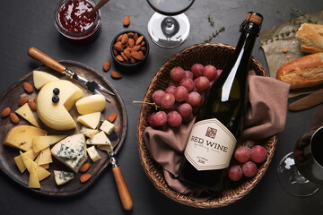 Canvas Print - Flat lay composition with bottle of red wine and snacks on black table