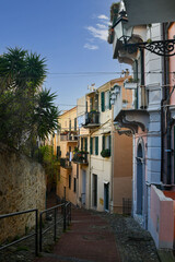 Sticker - A narrow uphill alley in the old town of Sanremo with the typical colored houses, Imperia, Liguria, Italy