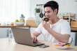 © Kawee - Asian business man eating unhealthy junk food while working from home.