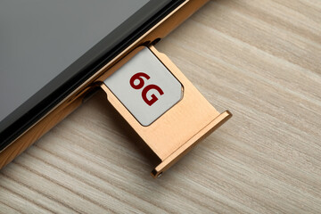 6G technology, Internet concept. SIM card in smartphone tray on wooden table, closeup