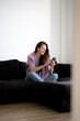 © Yurii Kushniruk - A happy woman in headphones is using her phone for social media