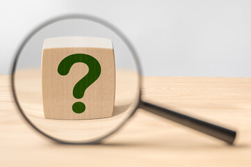 Fototapete - Search for an answer to question. Magnifying glass with question mark in focus on wooden cube. Research, searching or investigating something