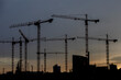 Beautiful night view of the construction of new houses. High construction cranes against the background of the night sky.
