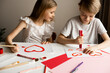 © Denira - Kids painting red valetine heart card on table at home