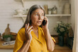 © shurkin_son - Elderly adorable Caucasian grandmother talking on phone with her grandson standing at kitchen having anxious and worried face expression, looking through window, waiting him for lunch