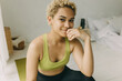 © shurkin_son - Portrait of teenage girl with perfect dark skin looking straight to camera, smiling touching her chin, feeling happy and energetic after fitness training at home, dressed in stylish leggings and top