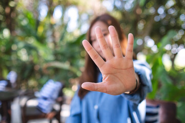 Wall Mural - A young woman outstretched hand and showing stop hand sign