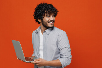 smiling young bearded indian man 20s years old wear blue shirt hold use work on laptop pc computer t