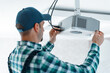 © Александр Маликов - The specialist independently connects a multimedia video projector for home theater or presentations mounted on a ceiling bracket.