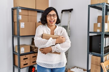 Wall Mural - Young latin woman ecommerce business worker hugging package order at office