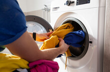 Man Loading The Washer Dryer With Clothes