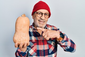 Poster - Handsome mature man holding healthy fresh pumpkin smiling happy pointing with hand and finger