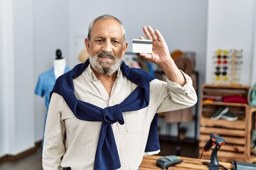 Poster - Senior grey-haired man smiling confident holding credit card at clothing store