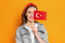 Student Girl Smiling And Holding A Small Turkish Flag Isolated Over Orange Background