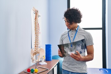 Sticker - Young hispanic man physiotherapist looking xray at rehab clinic