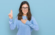Young beautiful woman wearing casual clothes and glasses smiling swearing with hand on chest and fingers up, making a loyalty promise oath