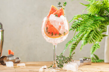 Wall Mural - Gin tonic trendy alcoholic cocktail drink with dry gin, bitter tonic, lemon juice, grapefruit, thyme and ice with bar tools. Wooden table background with copy space