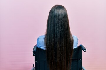 Poster - Beautiful woman with blue eyes sitting on wheelchair standing backwards looking away with crossed arms