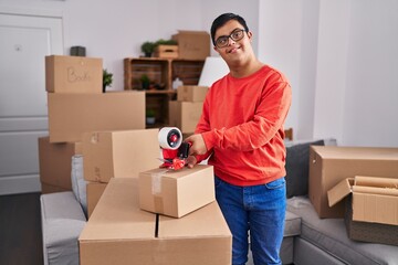 Wall Mural - Down syndrome man smiling confident packing cardboard box at new home