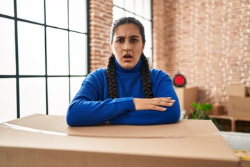 Poster - Young hispanic woman moving to a new home in shock face, looking skeptical and sarcastic, surprised with open mouth