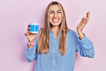 Canvas Print - Beautiful hispanic woman holding earwax cotton removers celebrating victory with happy smile and winner expression with raised hands