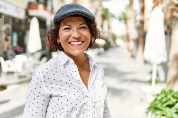 Middle age latin woman smiling happy standing at the city.