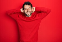 Handsome Man With Beard Wearing Casual Red Sweater Relaxing And Stretching, Arms And Hands Behind Head And Neck Smiling Happy