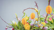 Wielkanocny bukiet  wiosennych kwiatów z gałązkami i papierowymi jajkami na grafitowym tle.