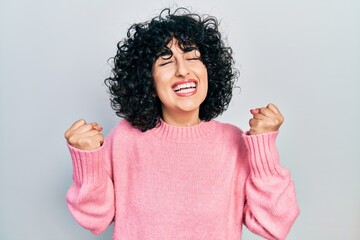 Sticker - Young middle east woman wearing casual clothes very happy and excited doing winner gesture with arms raised, smiling and screaming for success. celebration concept.