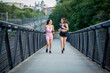 © luisrojasstock - young female couple running in sportswear on a bridge