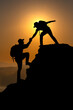 © noon@photo - Two backpack Man  adventure travel concept.Help and assistance concept silhouette of two people climbing a mountain and helping