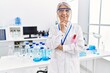 © Krakenimages.com - Middle age grey-haired woman wearing scientist uniform standing with arms crossed gesture at laboratory