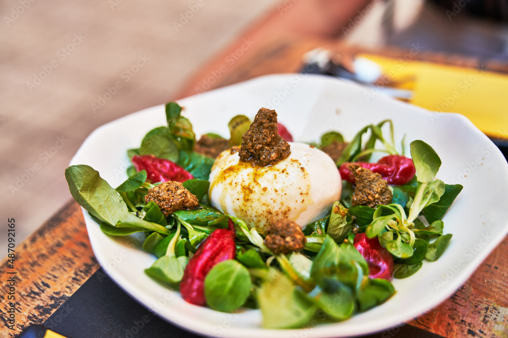 Beautiful burrata cheese with pesto on lambs lettuce salad image