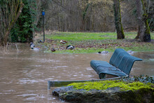 Walkway And Bench Flooded By A River With Muddy Water