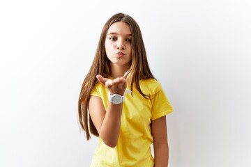 Poster - Young brunette teenager standing together over isolated background looking at the camera blowing a kiss with hand on air being lovely and sexy. love expression.