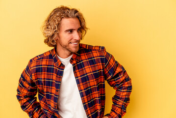 Wall Mural - Young caucasian man isolated on yellow background confident keeping hands on hips.